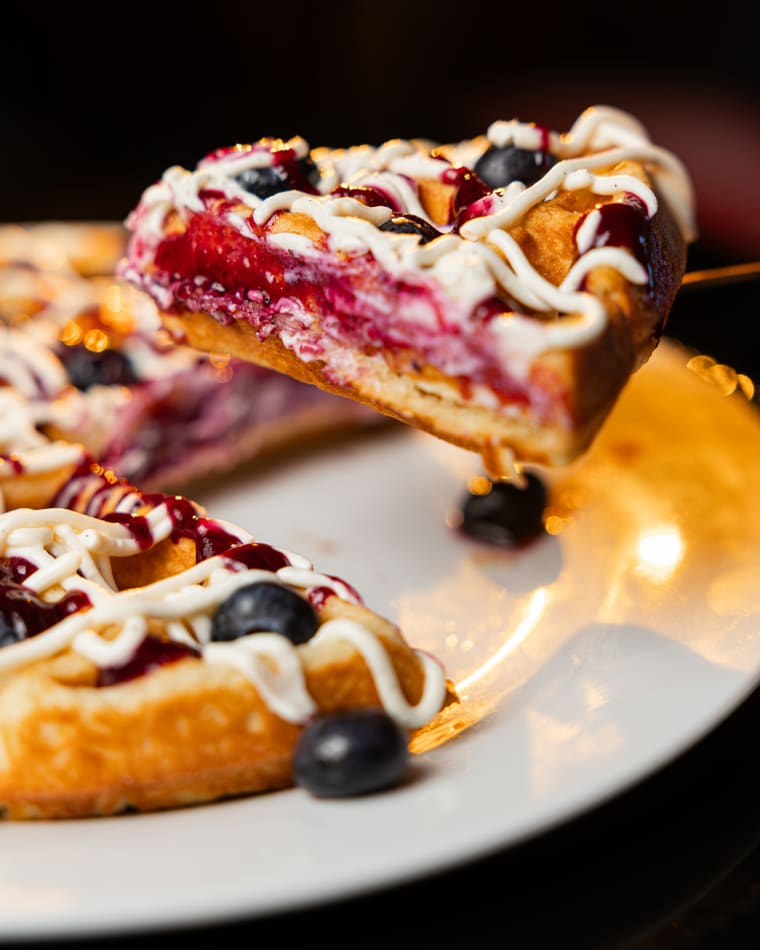 A slice of berry waffle raised from the plate